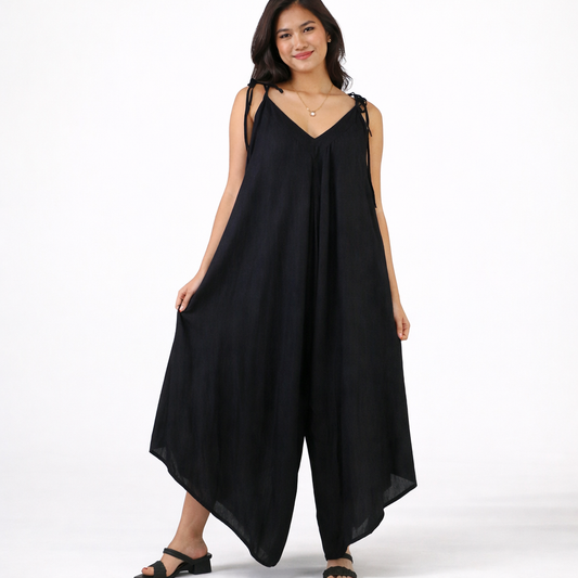 Woman wearing black flowy wide-leg jumpsuit with adjustable tie straps, V-neckline, and side pockets